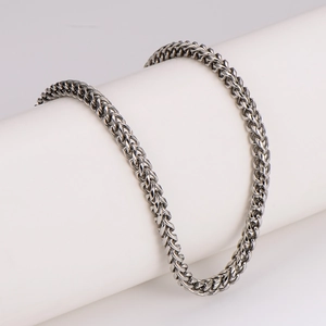 Polished silver stainless steel Cuban link necklace for men on white jewelry stand