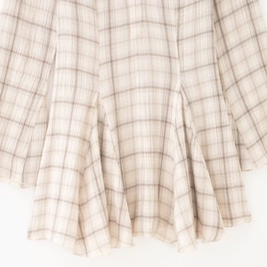 Robe à col en V à carreaux et manches longues montrant le drapé du tissu texturé