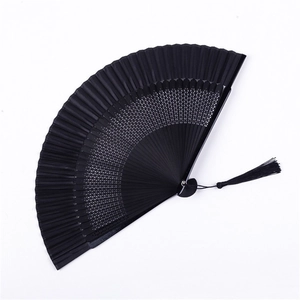 Detailed view of a black Chinese folding fan with intricate hollow patterns and silk tassel