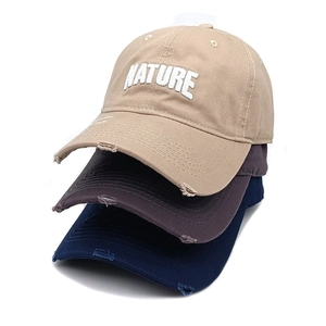 Detailed macro view of distressed cotton baseball caps featuring nature letter embroidery