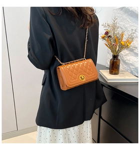 Close-up of brown quilted shoulder bag with gold chain strap on a model's shoulder