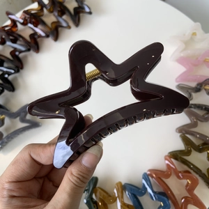 Detailed view of hollow star hair claw clips in various colors and metallic spring