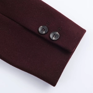 Detail of wool coat cuffs featuring double black buttons and soft wine red fabric