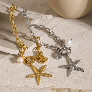 Detail of 18k gold and silver starfish bracelets with shell charms and sea pearls