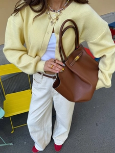 Close-up of brown leather handbag texture with gold buckle and soft handle detail