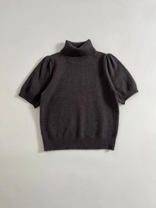 Detailed view of the dark grey knit top showing high collar and puff sleeve ribbing