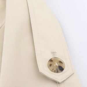 Close-up of beige twill windbreaker fabric featuring a stylish tortoise shell button detail