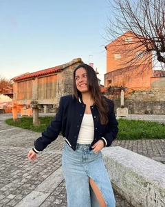 Scatto all'aperto di una giacca da baseball blu scuro abbinata a una gonna in denim