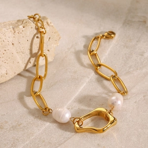 Detailed macro view of 18k gold paperclip chain bracelet with white pearls on stone
