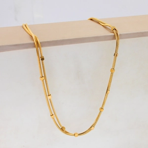 Detail of double-layer golden snake chain with minimalist cubic bead accents and high polish
