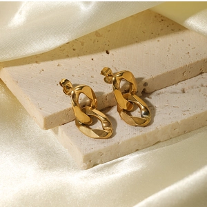 Detail of 18K gold-plated chain link earrings on natural stone and soft silk fabric