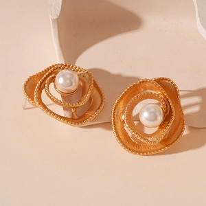 Macro shot of vintage gold spiral flower petal earrings with white faux pearl center