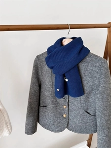 Dettaglio di sciarpa in lana a coste blu scuro abbinata a un cappotto grigio