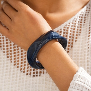 Detail of dark blue marble resin chunky bracelet worn by a model against white fabric