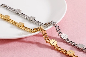 Detail view of gold and silver four-leaf clover bracelets on white ceramic plate