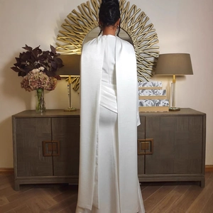 Detail of elegant white satin dress featuring back capelet and pleated waist structure