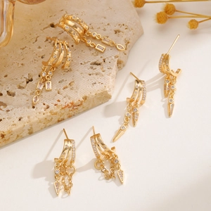 Detailed view of gold tassel earrings set with cubic zirconia on a stone pedestal