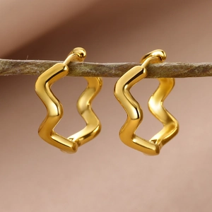 Macro shot of 18k gold plated wave-shaped earrings on a natural wooden branch