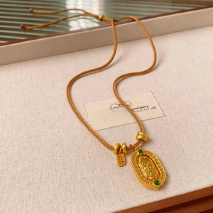 Close-up of golden dragon pendant with green gem on a yellow braided rope chain necklace