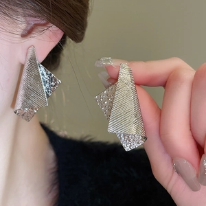 Detail of silver irregular geometric metal earrings with brushed and hammered textures
