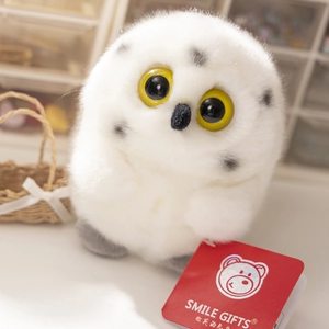 Close-up of white owl plush with big yellow eyes and branded Smile Gifts red tag