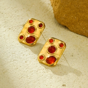 Detailed shot of retro gold rectangle stud earrings with five red resin gemstones