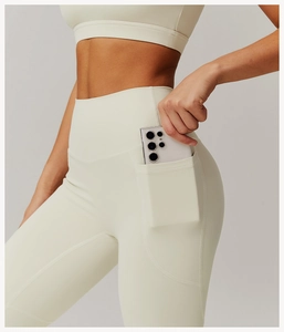 Close-up of functional side pocket on cream high-waisted yoga pants holding a smartphone
