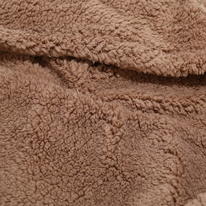 Macro view of plush brown sherpa fleece fabric showing thick winter texture