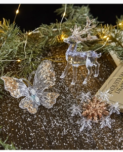 Detail of transparent acrylic Christmas ornaments with gold sequins on snow background