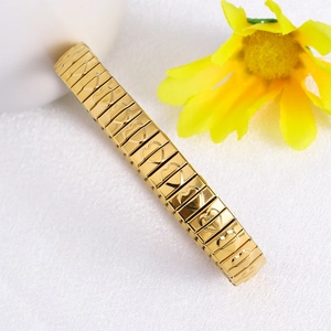 Macro detail of golden stretch bracelet featuring engraved heart patterns on links