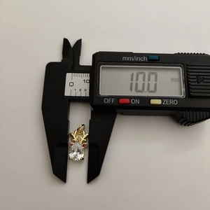 Close-up of golden reindeer pendant with shell pearl measuring 10.0mm on a digital caliper
