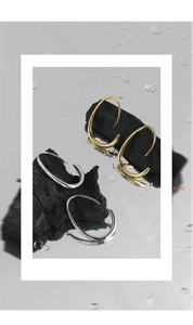 Dettaglio artistico di orecchini a C oro e argento su una superficie a specchio bagnata