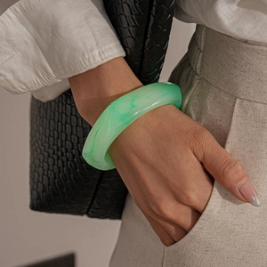 Close-up of a pale green marbled resin wide bangle worn with a minimalist outfit