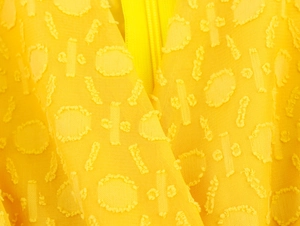 Makroaufnahme von gelbem Jacquard-Stoff mit geometrischer Textur und verdecktem Reißverschluss