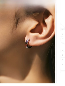 Macro shot of silver huggie hoop earring with rainbow square gems on earlobe