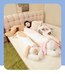 Three soft cartoon plush dog bolsters shown with model in cozy bedroom setting