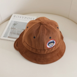Détail d'un chapeau cloche en velours côtelé marron avec écusson d'ours pour enfants