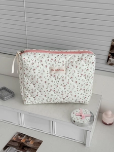 Détail d'une trousse de maquillage matelassée fleurie avec fermetures éclair roses