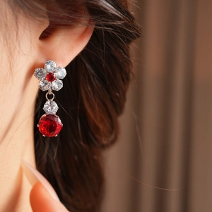 Macro detail of luxury flower drop earrings with red and white zircons on model