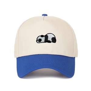 Detail of panda embroidery on two-tone beige and royal blue baseball cap with fine stitching
