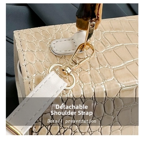 Detail of the golden metal buckle and faux crocodile leather texture on the handbag