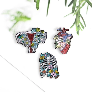 Artistic anatomy enamel pins with colorful blooming flowers featuring heart, ribs and uterus