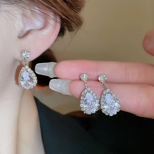 Elegant silver teardrop zircon earrings and necklace set on a model and held by hand