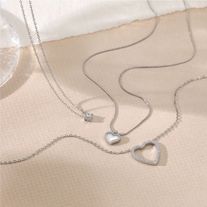 Macro detail of three silver heart pendants with zircon stones on minimalist chains