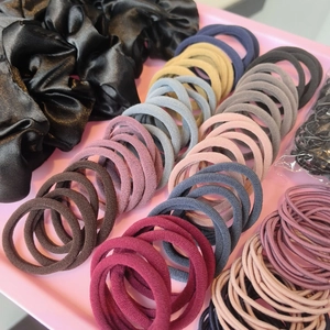 Detail view of black satin scrunchie and colorful elastic hair ties set in a tray