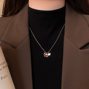 Close-up of gold-plated necklace with brown puppy and crystal heart charms on model