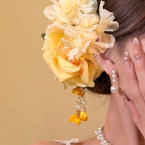 Detailed view of elegant yellow fabric rose hair clip with pearl tassels and floral charms