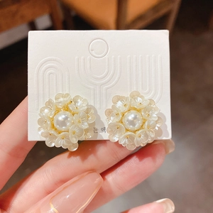 Close-up of floral stud earrings with creamy petals and central faux pearls