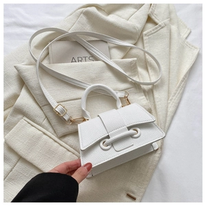 Close-up of a white lychee grain PU leather mini bag with gold hardware on a beige blazer