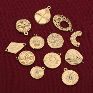 Golden stainless steel bohemian pendants with evil eye and sun motifs on red fabric